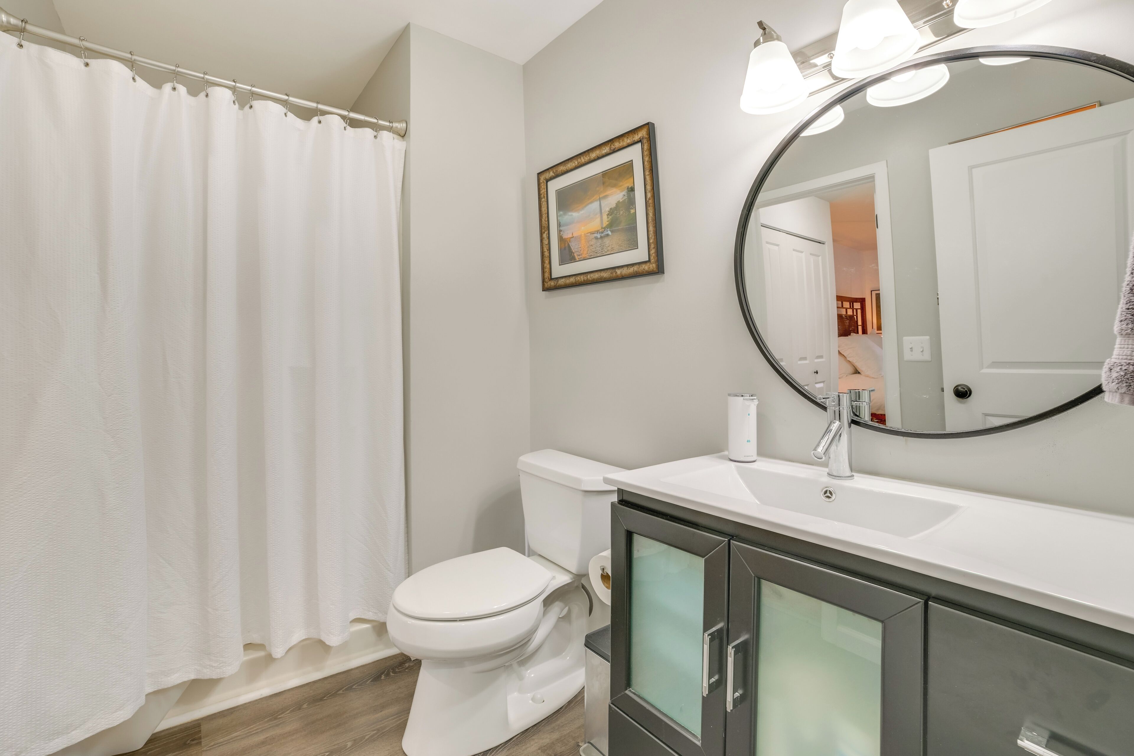 A bathroom with a white toilet, a white sink with a mirror above it, and a shower curtain.