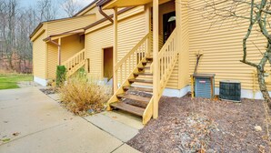 Une maison jaune avec un porche à l’avant et un escalier menant à l’entrée.
