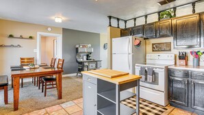 Una cocina con mesa, sillas, refrigerador, estufa y armarios.