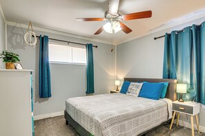 A bedroom with a bed, a nightstand, a ceiling fan, and a window with curtains.