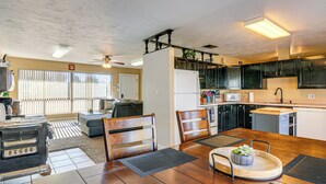 Una cocina moderna con armarios oscuros, un refrigerador blanco y una zona de comedor con sillas y una mesa de madera.