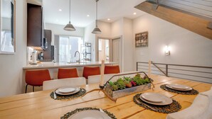 Un comedor con una mesa de madera dispuesta para cuatro personas, rodeada de sillas rojas. Un macetero con suculentas está colocado sobre la mesa.