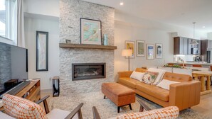 Un salón moderno con una pared de piedra, una chimenea, un sofá y un televisor.