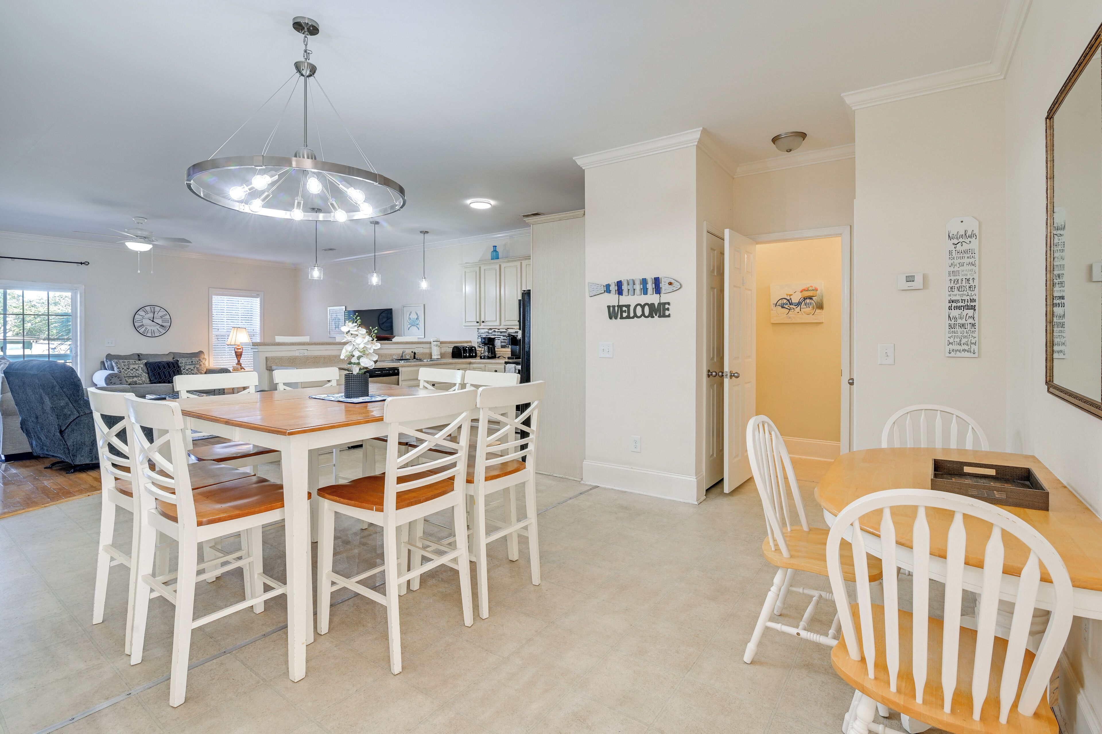 A modern kitchen with white cabinetry, a wooden dining table, and a chandelier.