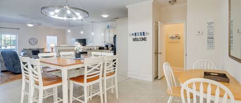 A modern kitchen with white cabinetry, a wooden dining table, and a chandelier.