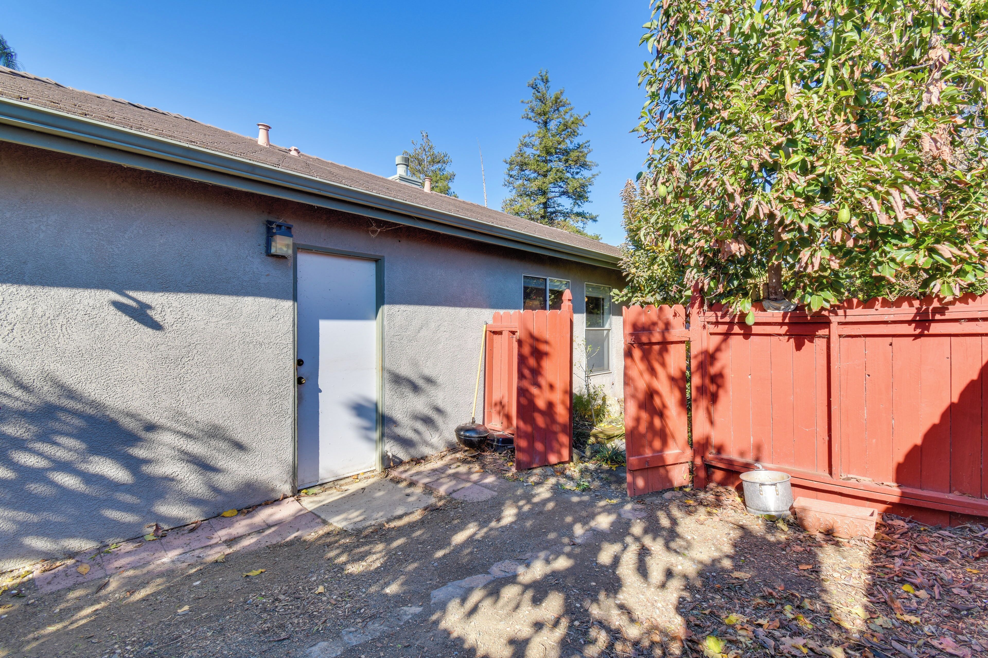 A garage with a red fence, a white door, and a tree casting shadows on the ground.