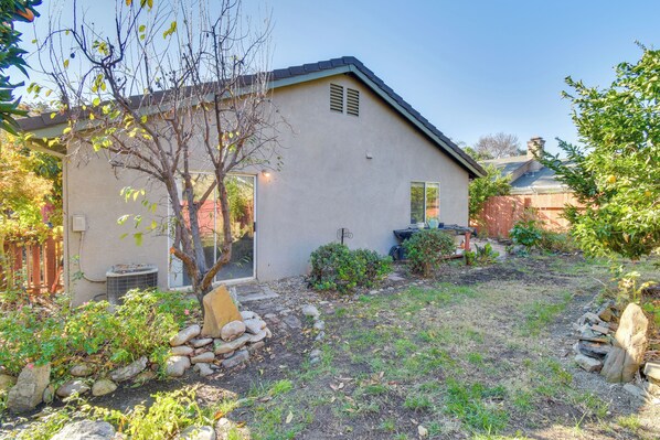 A house with a sloped roof, a small front porch, and a garden with rocks and plants.