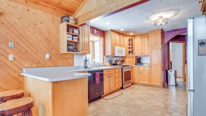 Eine Küche mit Holzausstattung, einer zentralen Kochinsel und einem Edelstahlkühlschrank.