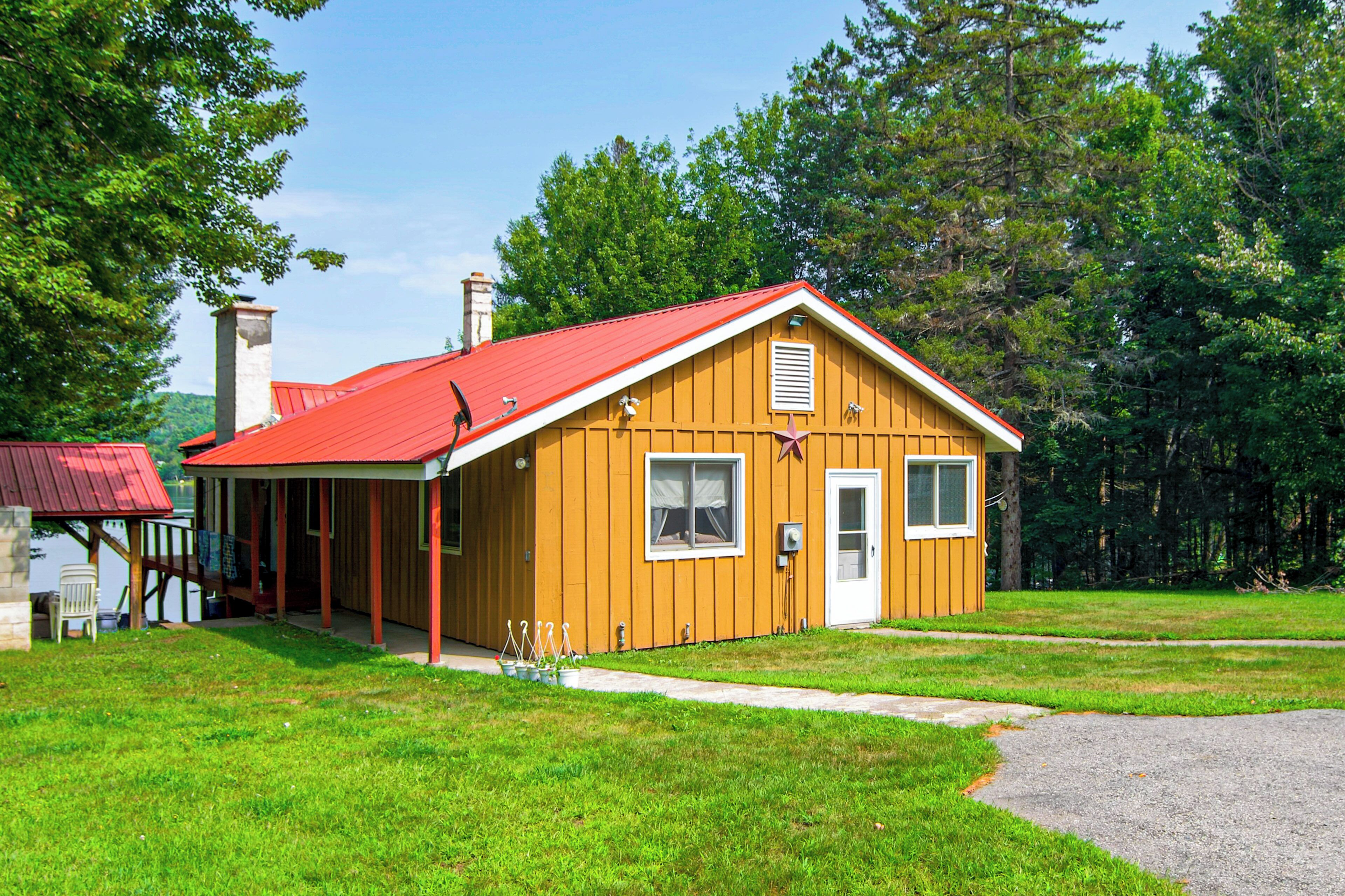 A small wooden cabin with a red roof, a porch, and a chimney.