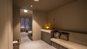 A modern hotel lobby with a reception desk, a seating area with a bench, and a hallway leading to a room with a large window and curtains. - Superior 1-bedroom Apartment (Schruns)