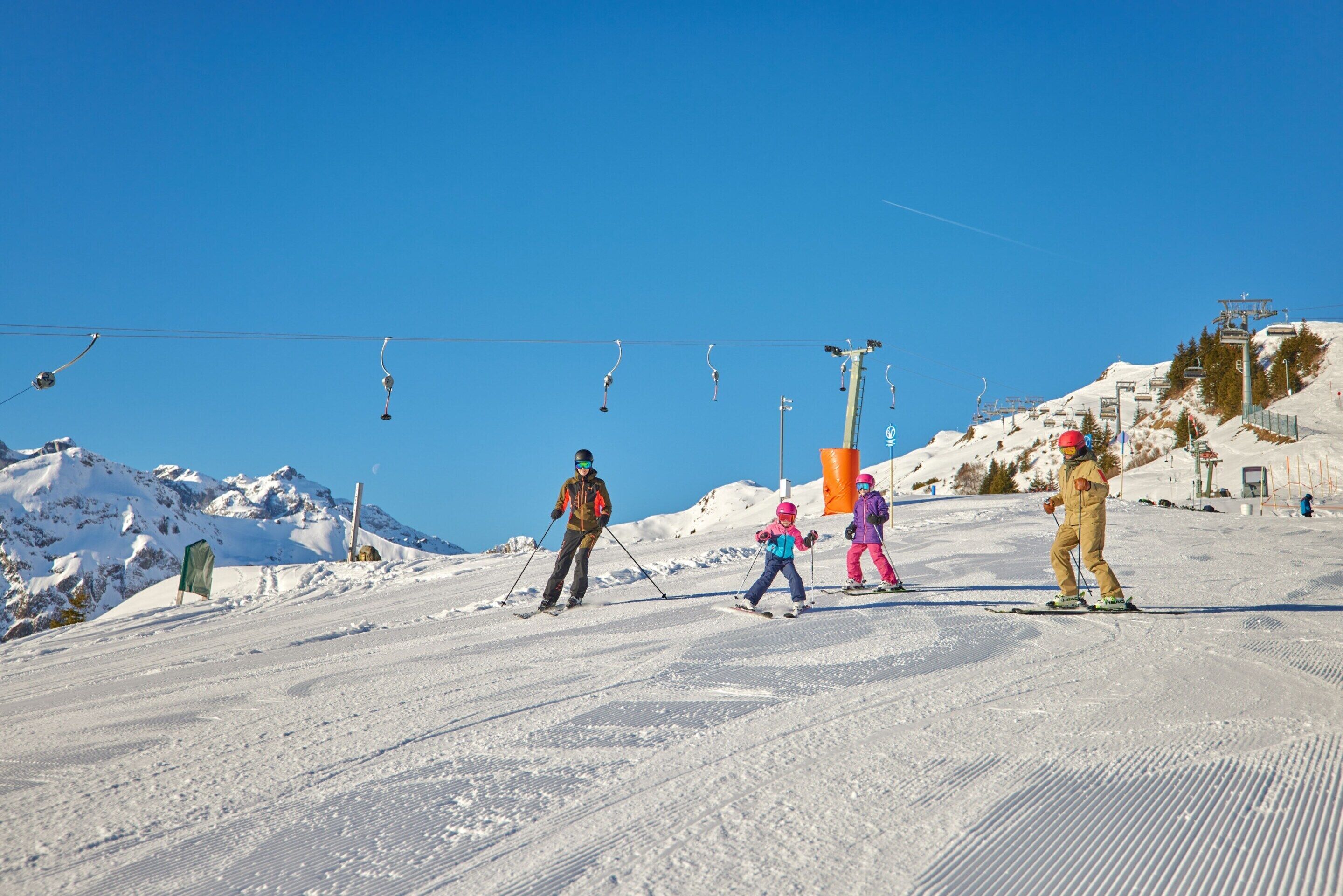 A ski slope with a clear blue sky, ski lifts, and skiers.