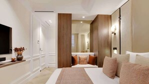 Habitación de hotel con una cama grande, un televisor de pantalla plana, un florero con flores secas y un panel de pared de madera.