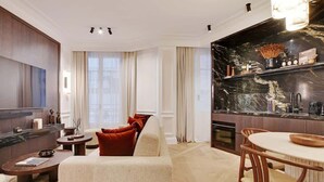 Una sala de estar moderna con un sofá beige, una mesa de centro redonda y un comedor con una mesa y sillas de madera.