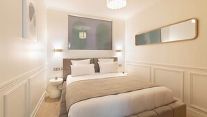Een moderne slaapkamer met een groot bed, nachtlampjes, een spiegel en een kroonluchter.