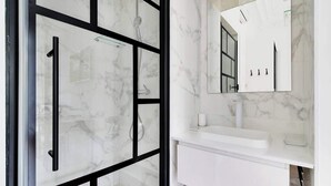 A modern bathroom with a glass shower enclosure, a white sink, and a large mirror.
