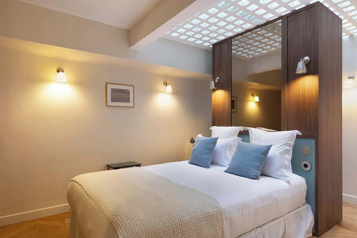 Une chambre avec un grand lit, des lampes de chevet, un miroir et une fenêtre de toit.