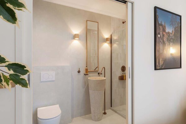Une salle de bain moderne avec un grand lavabo à texture, une douche en verre et un miroir fixé au mur.