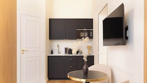 A modern kitchen with dark cabinets, a microwave, and a vase with dried flowers on the counter. - A Romantic Studio with Services in Opera (Paris)