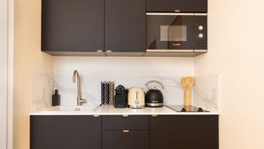 A modern kitchen with a Bosch microwave, a kettle, a toaster, and a sink. - A Romantic Studio with Services in Opera (Paris)