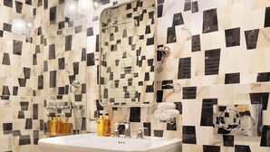 A bathroom with a checkered black and white tile floor, a white sink with chrome fixtures, and a white toilet. - A Romantic Studio with Services in Opera (Paris)