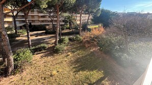 A courtyard with trees, a pathway, and a building in the background. - Le balcon de Funès, 4min walk from the beach, with swimming pool, parking, 70m2 7personnes (Fréjus)