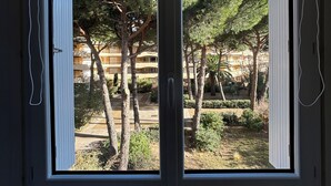 A window with a view of a courtyard with trees and a building in the background. - Le balcon de Funès, 4min walk from the beach, with swimming pool, parking, 70m2 7personnes (Fréjus)
