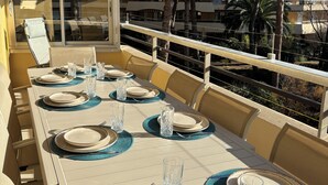 A dining area with a table set for six, outdoor seating, and a view of a residential building and trees. - Le balcon de Funès, 4min walk from the beach, with swimming pool, parking, 70m2 7personnes (Fréjus)