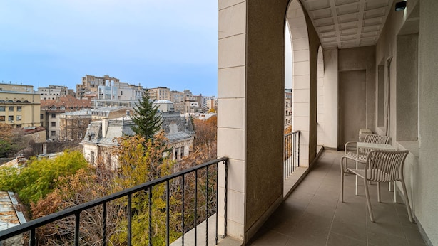 A balcony with a view of a cityscape, featuring a tiled floor and a railing. - Loggia Luxe 5BR Living in Universitatii Area (Bucharest)