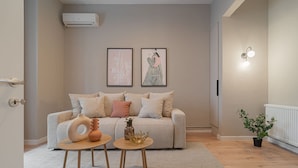 A modern living room with a beige sofa, two side tables, and a potted plant. - Loggia Luxe 5BR Living in Universitatii Area (Bucharest)