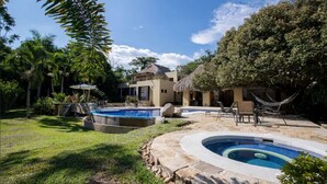 Un patio trasero con piscina, sillas de descanso y una hamaca.