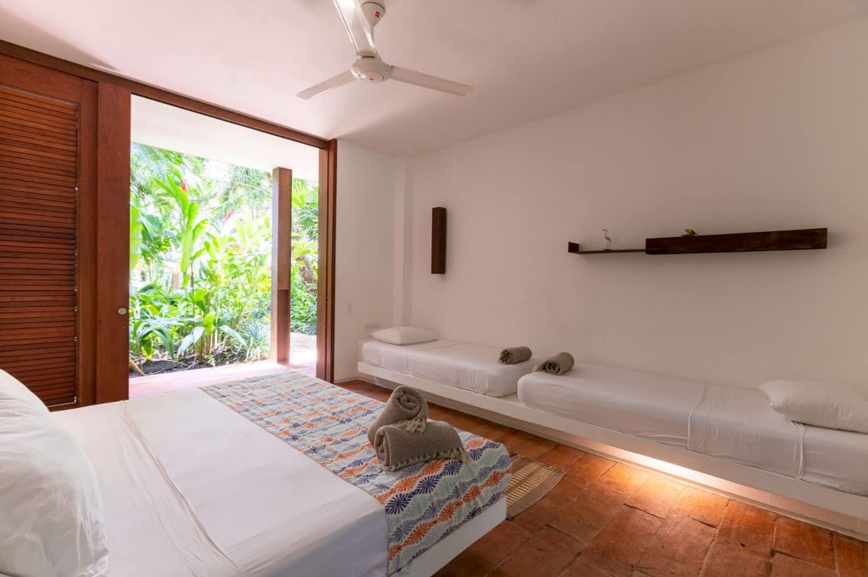 A bedroom with a bed, a bench, and a ceiling fan.