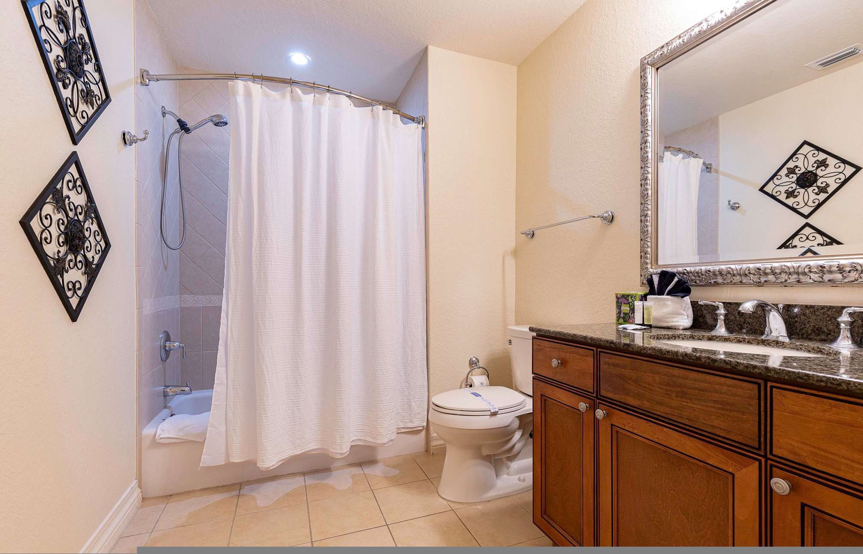Une salle de bain équipée d’une douche, de toilettes, d’un meuble-lavabo et d’un miroir.