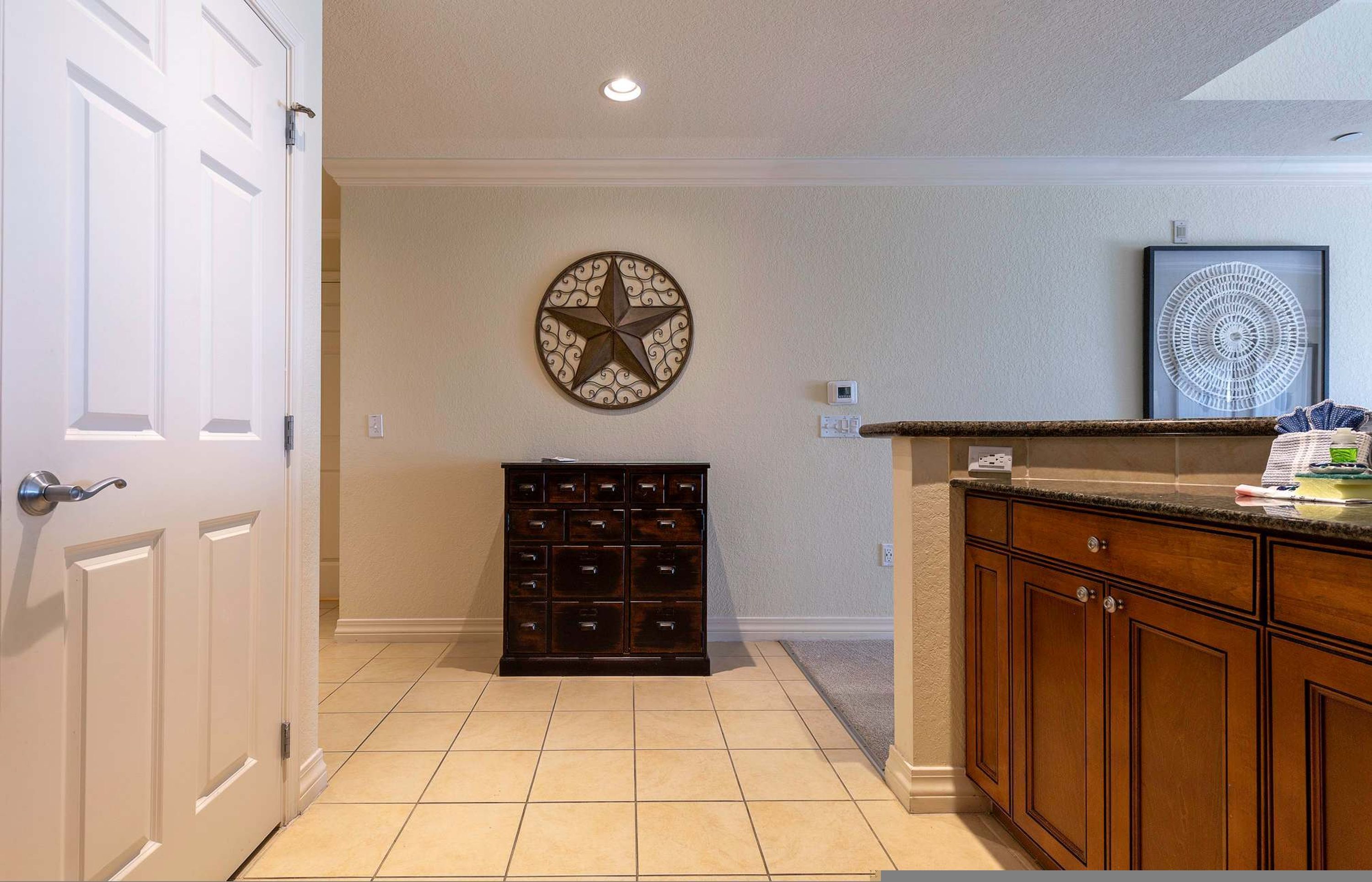 Una cocina con un armario de madera, un adorno en la pared con forma de estrella y una obra de arte enmarcada.