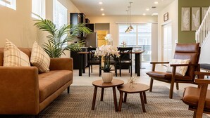 Un salon chaleureux avec un canapé marron, une table basse et un coin repas comprenant une table et des chaises.