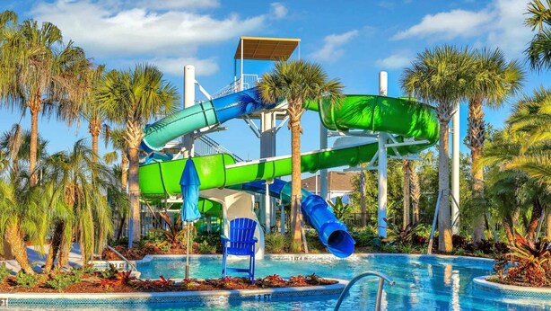 Un parc aquatique doté d’une grande piscine, de toboggans et de palmiers.