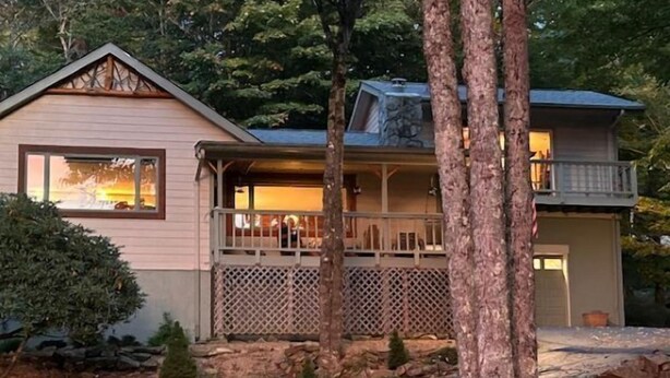 A cabin with a porch, a deck, and a stone wall.