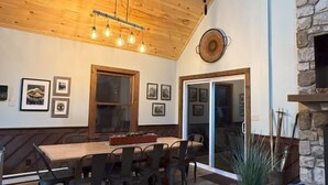 Un comedor amplio con una mesa y sillas de madera, una chimenea de piedra y un ventanal grande.