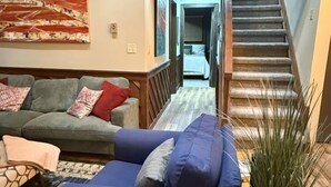 Una sala de estar con un sofá azul, un sofá verde y una escalera de madera.