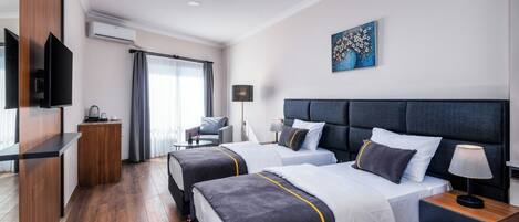 Una habitación de hotel con dos camas, televisión, escritorio y un cuadro en la pared.