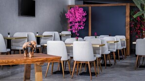 Un comedor moderno con sillas tapizadas en gris, mesas de madera y una figurita decorativa de elefante sobre una mesa.