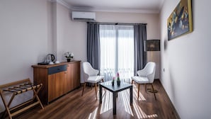 Una habitación moderna con un escritorio de madera, dos sillas blancas, una mesita y un cuadro en la pared.