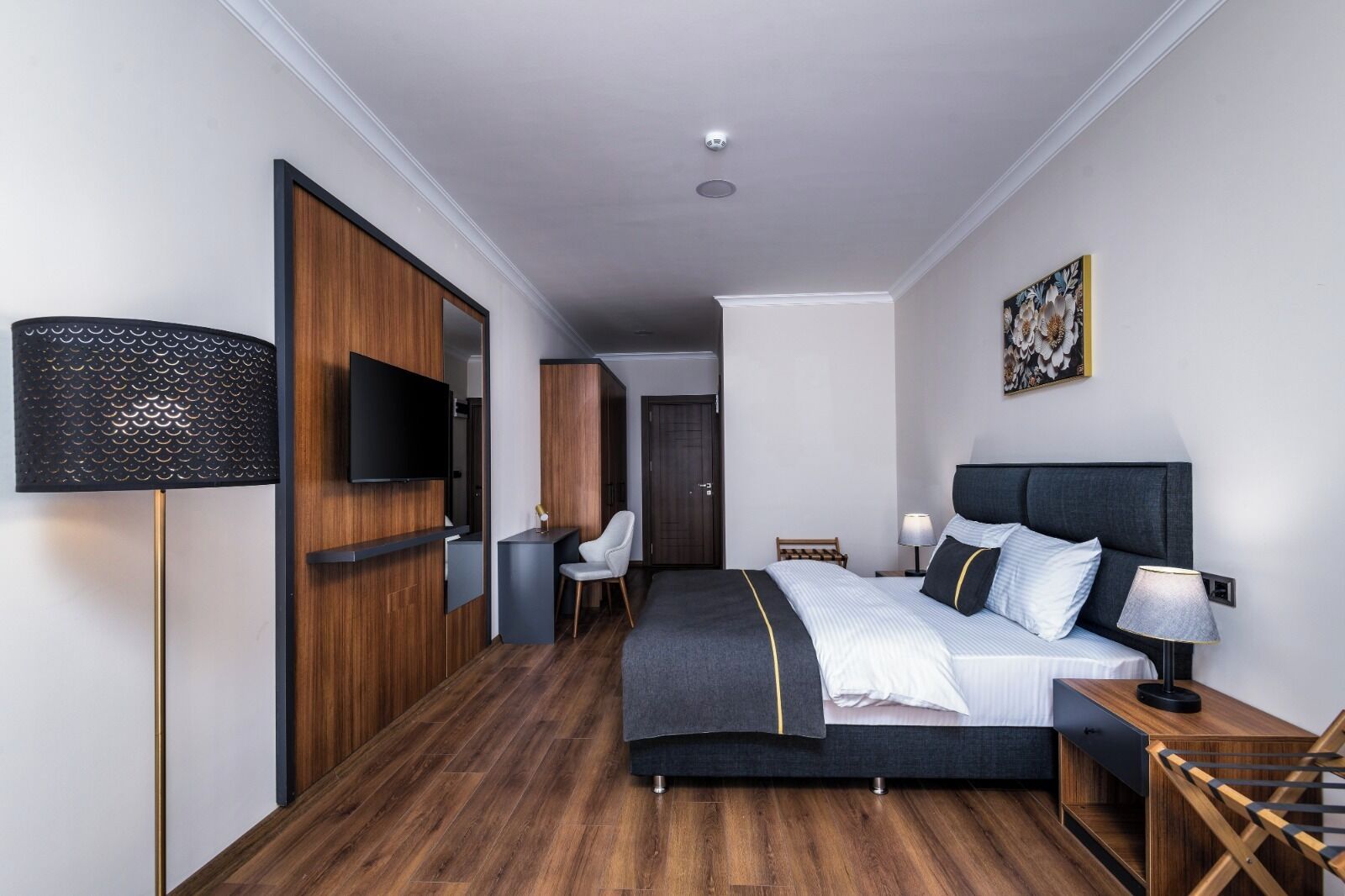 Une chambre d’hôtel moderne, dotée d’un grand lit, d’un bureau, d’une chaise, d’une télévision et d’un tableau au mur.