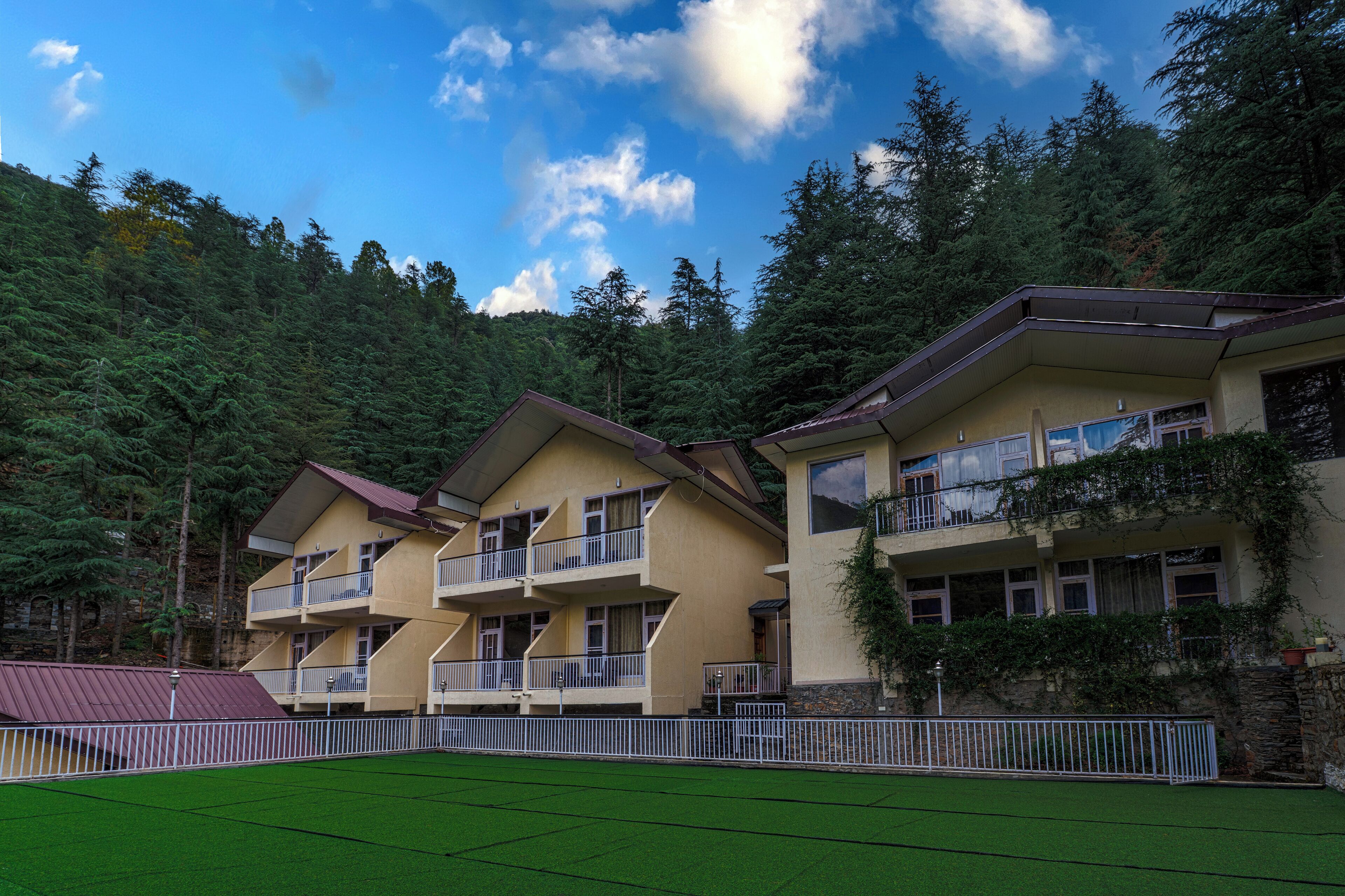 A multi-story hotel with balconies, surrounded by forested hills.