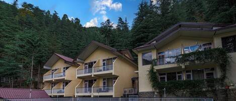 A multi-story hotel with balconies, surrounded by forested hills.