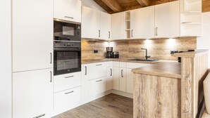 Una cocina moderna con armarios blancos, encimera de madera y horno empotrado.