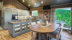 Une cuisine moderne dotée d’un îlot central, d’une table à manger et de chaises. Une fenêtre offre une vue sur la verdure.