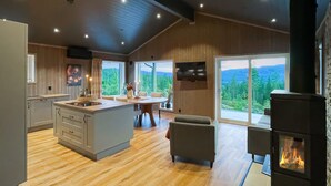 Une cuisine moderne dotée d’un îlot central, d’un coin repas avec vue et d’une cheminée.