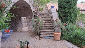 A stone staircase leading up to a building with a tiled roof, surrounded by greenery and potted plants. - The Mas of Largellas (Balazuc)