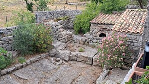 An archaeological site with stone walls and a tiled-roof structure. - The Mas of Largellas (Balazuc)