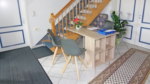 Un petit bureau avec un bureau, deux chaises, une plante et un escalier.